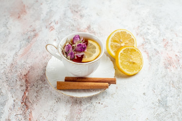 Bezpłatne zdjęcie filiżanka herbaty z widokiem z przodu z plastrami cynamonu i cytryny na jasnej białej przestrzeni