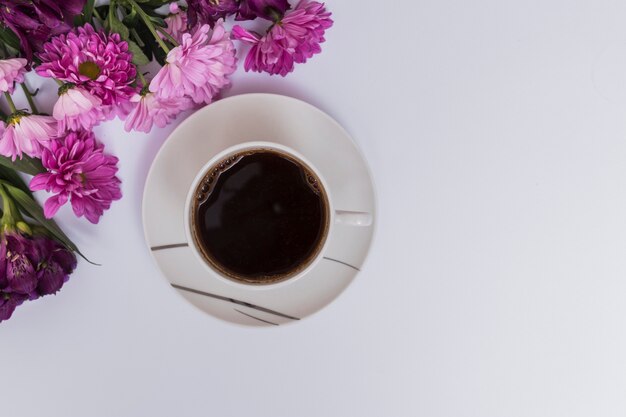 Filiżanka kawy i fioletowe kwiaty