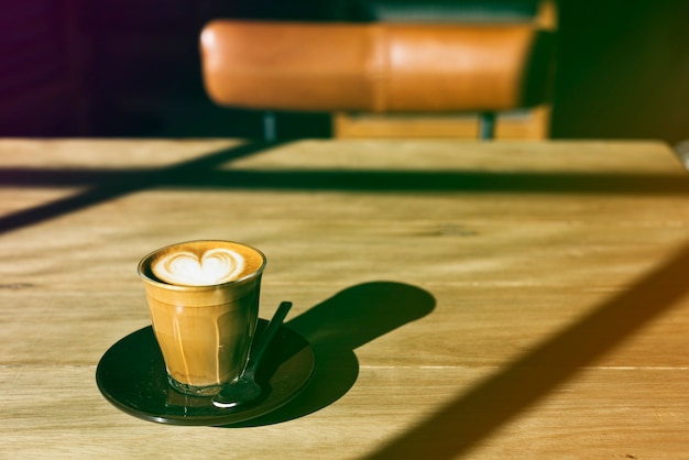 Bezpłatne zdjęcie filiżanka kawy na drewnianym stole z gradientowym stylu fotografii