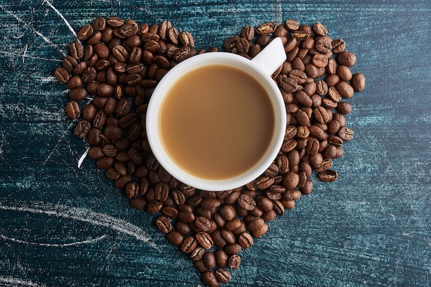 Filiżanka kawy na ziarnach w kształcie serca.