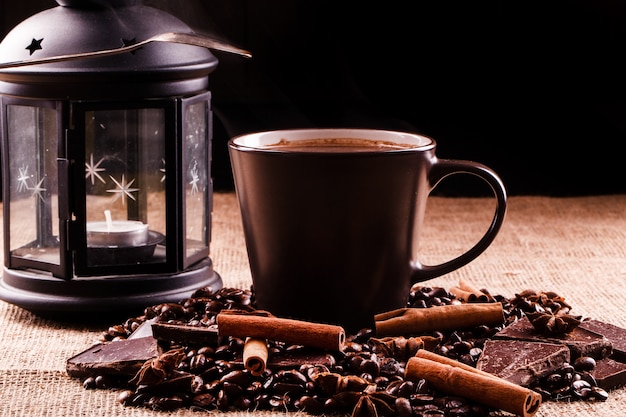 Filiżanka kawy stoi na ziarna kawy i czekolady
