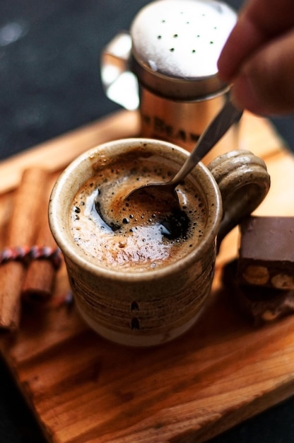 Filiżanka kawy z cynamonem i czekoladowymi ciasteczkami na drewnianej desce