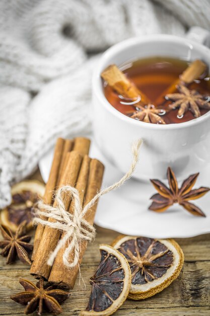 filiżankę gorącej herbaty z cytryną, laską cynamonu i łyżką brązowego cukru na drewnie