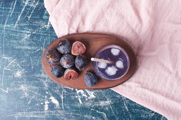 Fioletowe figi przy filiżance napoju na niebiesko.