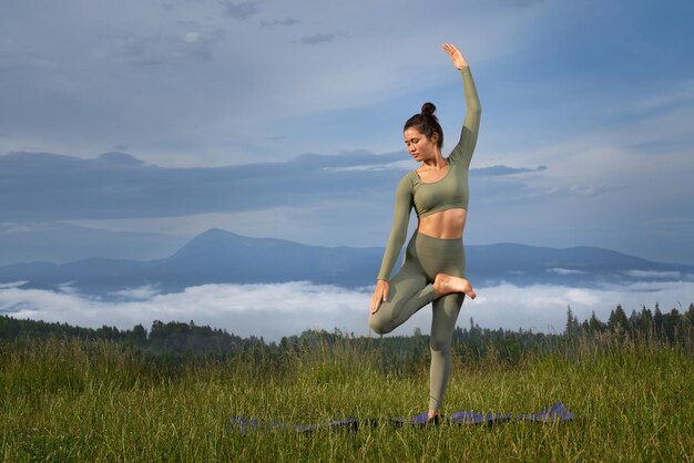 Fitness kobieta robi ćwiczenia jogi wśród zielonej przyrody