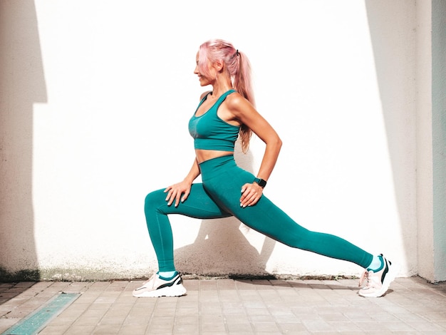 Fitness Uśmiechnięta Kobieta W Zielonej Odzieży Sportowej Z Różowymi Włosami Młody Piękny Model Z Idealnym Ciałemkobieta Pozująca Na Ulicy W Pobliżu Białej ścianywesoły I Szczęśliwy Rozciąganie Się Przed Treningiem