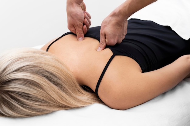 Bezpłatne zdjęcie fizjoterapeuta wykonujący masaż pleców na pacjentce