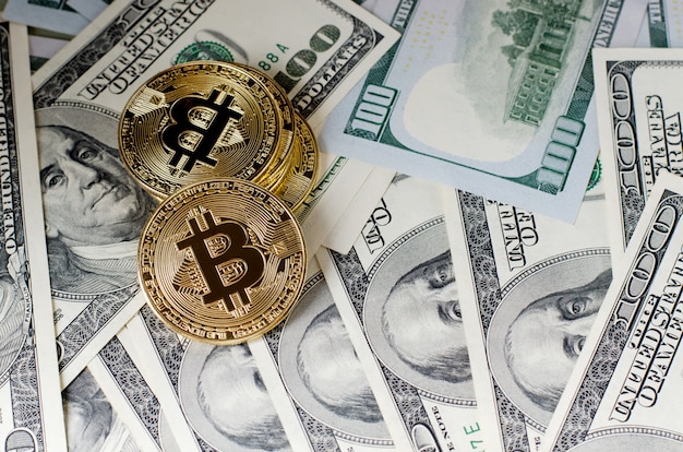 Fizyczna złocista bitcoin moneta przeciw dolarowym rachunkom i smartphone na purpurowym tle.
