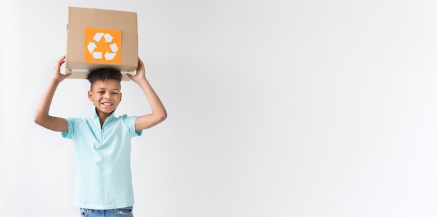 Bezpłatne zdjęcie frontowego widoku chłopiec młody mienie przetwarza pudełko z kopii przestrzenią