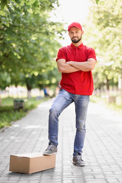 Frontowego widoku młody doręczeniowy mężczyzna pozuje outdoors