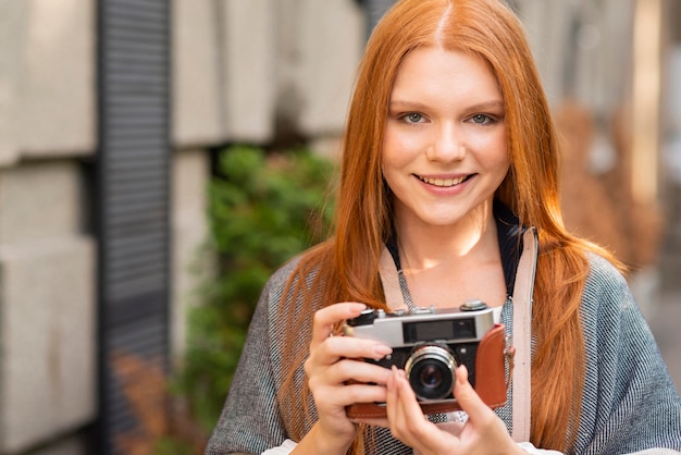 Bezpłatne zdjęcie frontowego widoku smiley kobiety mienia kamera