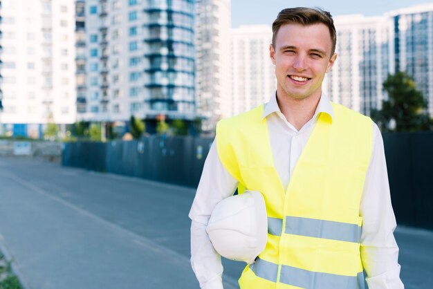 Frontowego widoku smiley młody człowiek z hełmem