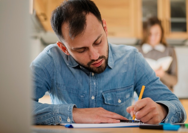 Frontowy Widok Mężczyzna Writing Na Notatniku Przy Biurkiem