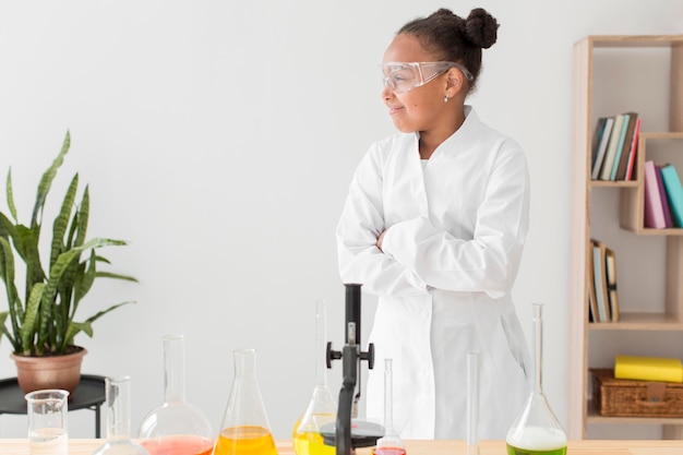 Frontowy widok młoda dziewczyna naukowiec w lab żakiecie z mikroskopu i kopii przestrzenią
