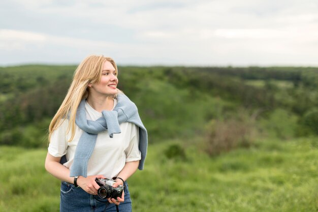 Frontowy widok pozuje outdoors kobieta podczas gdy trzymający kamerę