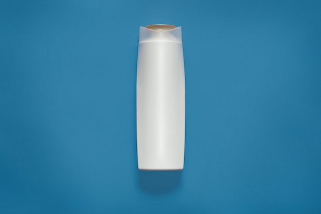 Frontowy widok pusta biała plastikowa kosmetyk butelka odizolowywająca na błękitnym studiu, pusty kosmetyczny zbiornik, wyśmiewa up i kopiuje przestrzeń dla reklamy lub promocyjnego teksta. Koncepcja Beuity.