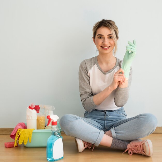 Frontowy widok smiley kobiety kładzenie na cleaning rękawiczce