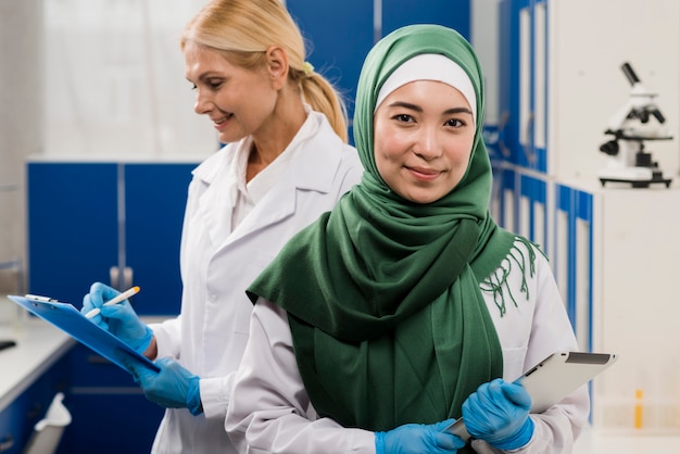 Frontowy widok żeński naukowiec z hijab pozuje w lab z kolegą