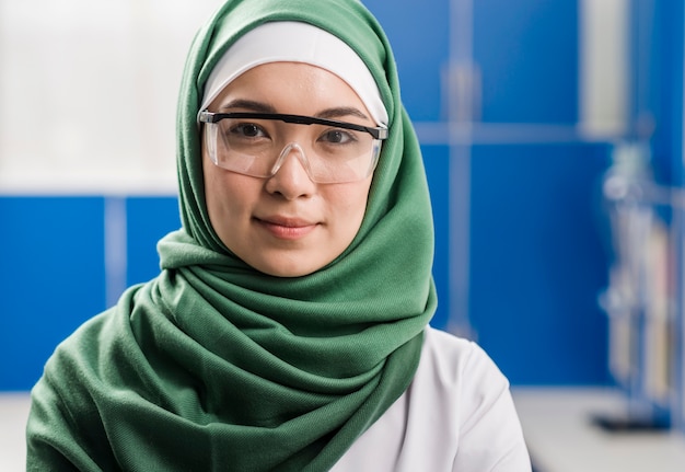 Bezpłatne zdjęcie frontowy widok żeński naukowiec z hijab pozuje w laboratorium