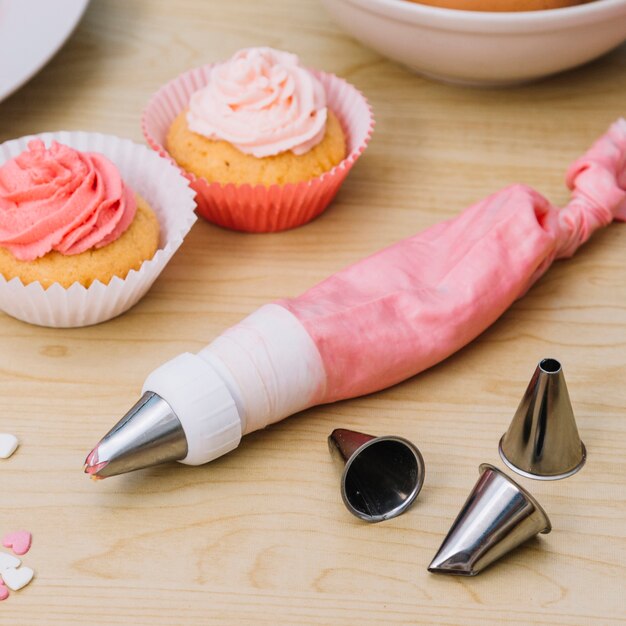 Frosting worek na napój wypełniony kremem; dysze; ciastko na drewniane biurko