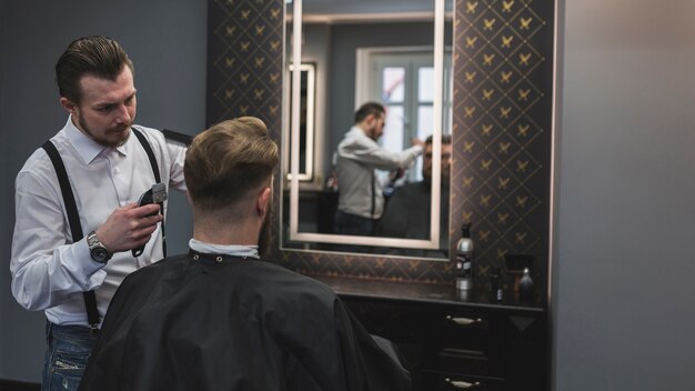 Fryzjer golenie klienta w pobliżu lustra