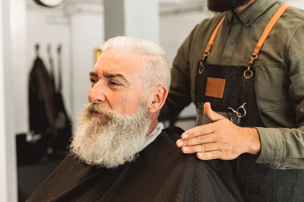 Fryzjer ocenia starszy klient w zakładzie fryzjerskim