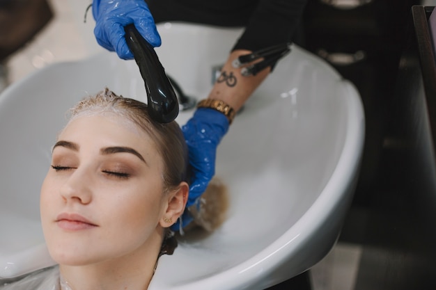 Bezpłatne zdjęcie fryzjerka myje włosy klienta w zlewie