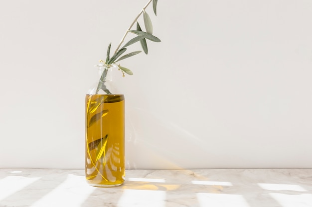 Bezpłatne zdjęcie gałązka w otwartej szklanej butelce z olejem na marmurowej posadzce