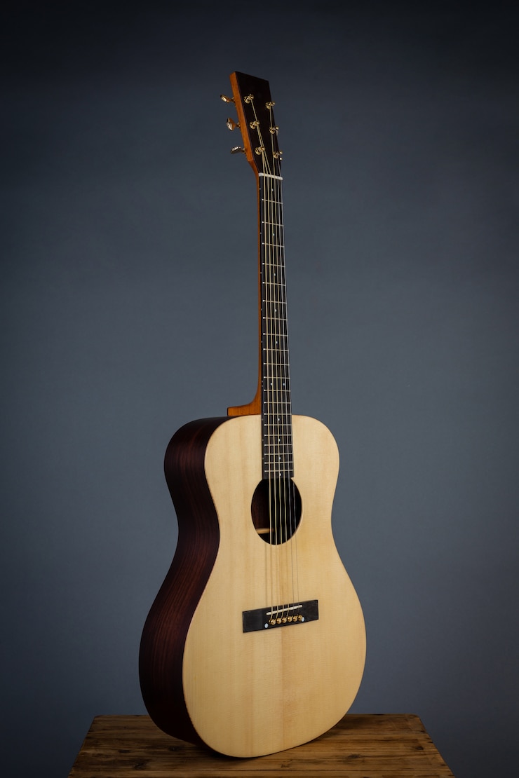 Bezpłatny plik Zdjęcie gitara akustyczna na krześle w czarnej ścianie.