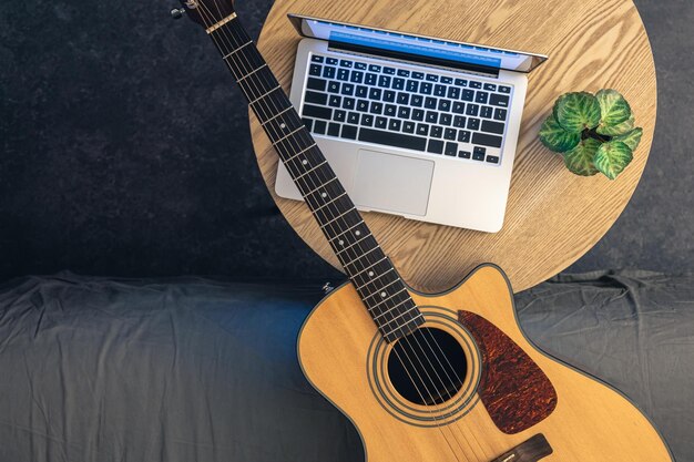 Gitarka akustyczna i laptop na drewnianym stole