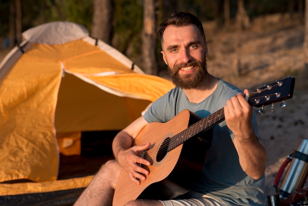 Gitarzysta patrząc na kamerę przy namiocie