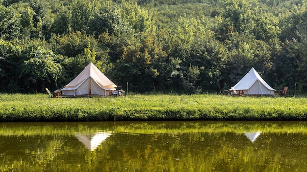 Glamping, kilka namiotów, jezioro na pierwszym planie, dookoła zgraja