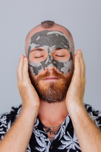 Bezpłatne zdjęcie gliniana maska na twarz młodego przystojnego mężczyzny w klinice piękności