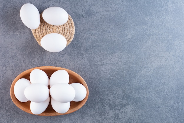 Bezpłatne zdjęcie gliniana miska pełna surowych białych jaj na kamiennym stole.