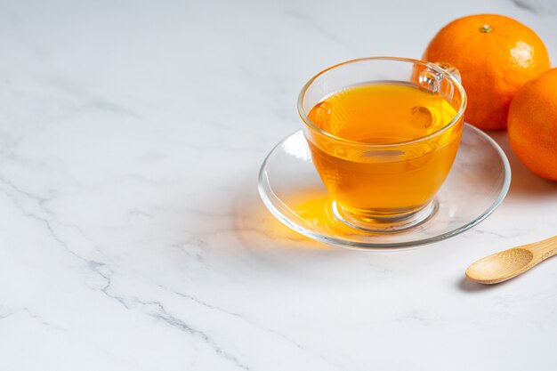 Gorąca herbata pomarańczowa i świeża pomarańcza na stole