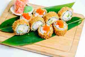Bezpłatne zdjęcie gorące bułki sushi z paluszkami krabowymi, awokado podawane na liściach na desce