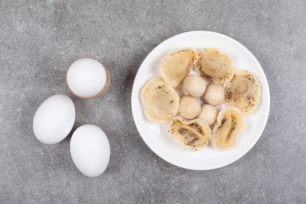 Gotowane pierogi i jajka na białym talerzu