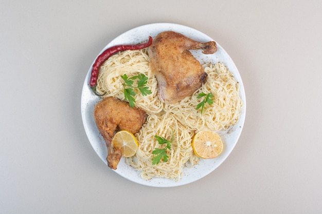 Gotowane spaghetti, papryka i udka z kurczaka na białym talerzu