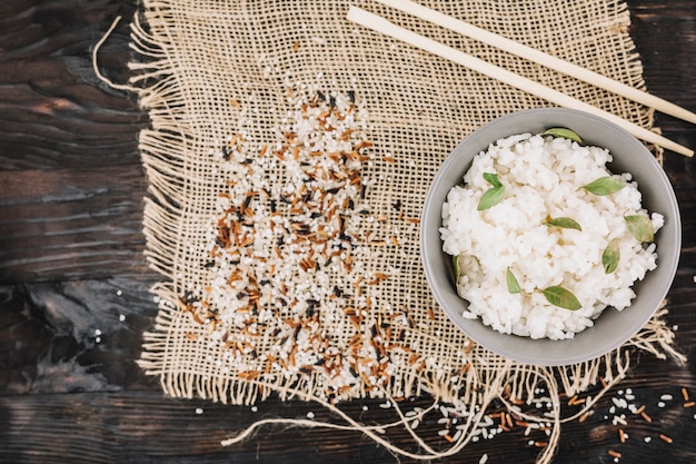Bezpłatne zdjęcie gotowany ryż w pobliżu pałeczki i rozlany ziarna