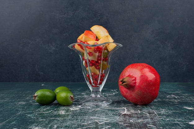 Granat, feijoas i szklanka mieszanych owoców na marmurowym stole
