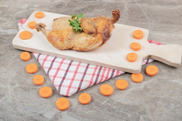 Bezpłatne zdjęcie grillowany kurczak na desce z plastrami marchwi.