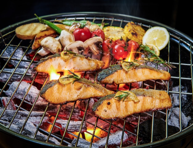 Bezpłatne zdjęcie grillowany łosoś z różnymi warzywami na patelni na płonącym grillu pieprz cytryna i sól, dekoracja ziołowa. selektywna ostrość. koncepcja zdrowego posiłku.