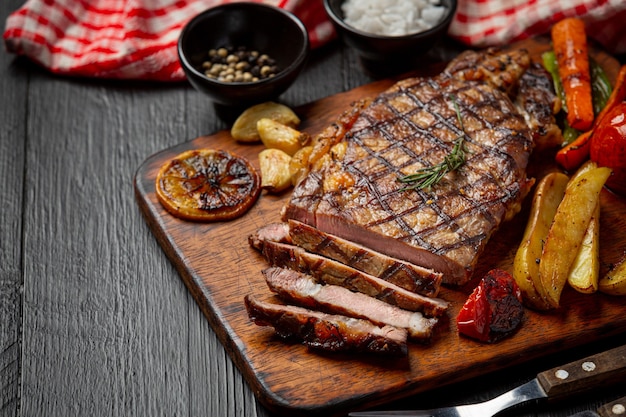 Grillowany stek wołowy na ciemnej drewnianej powierzchni.