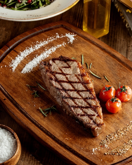 Grillowany stek wołowy podawany z ziołowymi solami i grillowanym pomidorem
