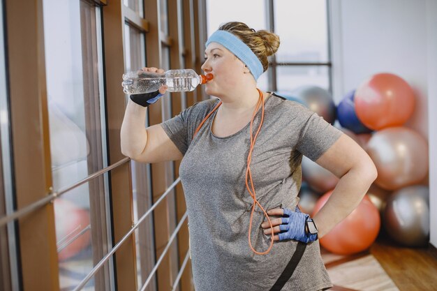 Gruba kobieta diety, fitness. Pani z liną. Kobieta w szarym stroju sportowym.