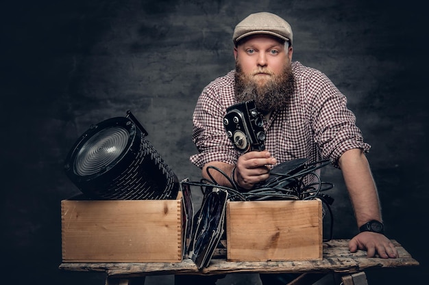 Bezpłatne zdjęcie gruby, brodaty mężczyzna hipster trzyma w ręku kamerę wideo 8 mm i kolorowe lampy w podsufitkach.