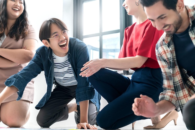 Bezpłatne zdjęcie grupa azjatyckich i kaukaskich młodych kreatywnych szczęśliwych cieszyć się śmiechem uśmiechem i wielkim sukcesem emocjami pracy zespołowej ludzie biznes startupowy przedsiębiorca przypadkowa burza mózgów spotkanie biznesowe biuro tło