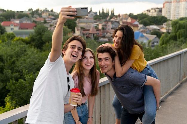 Grupa czterech przyjaciół spędzających razem czas na świeżym powietrzu i robiących selfie