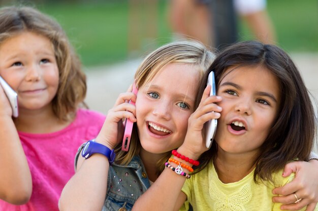 Grupa dzieci używających telefonów komórkowych w parku.
