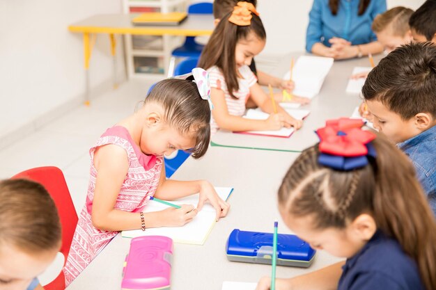 Grupa dzieci w wieku przedszkolnym pracująca nad zadaniem pisarskim w klasie